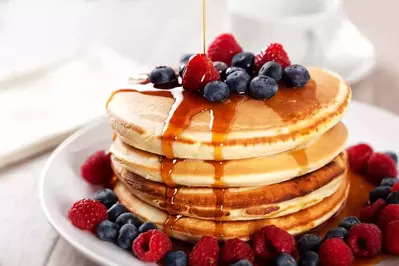 A stack of delicious pancakes with berries and syrup.